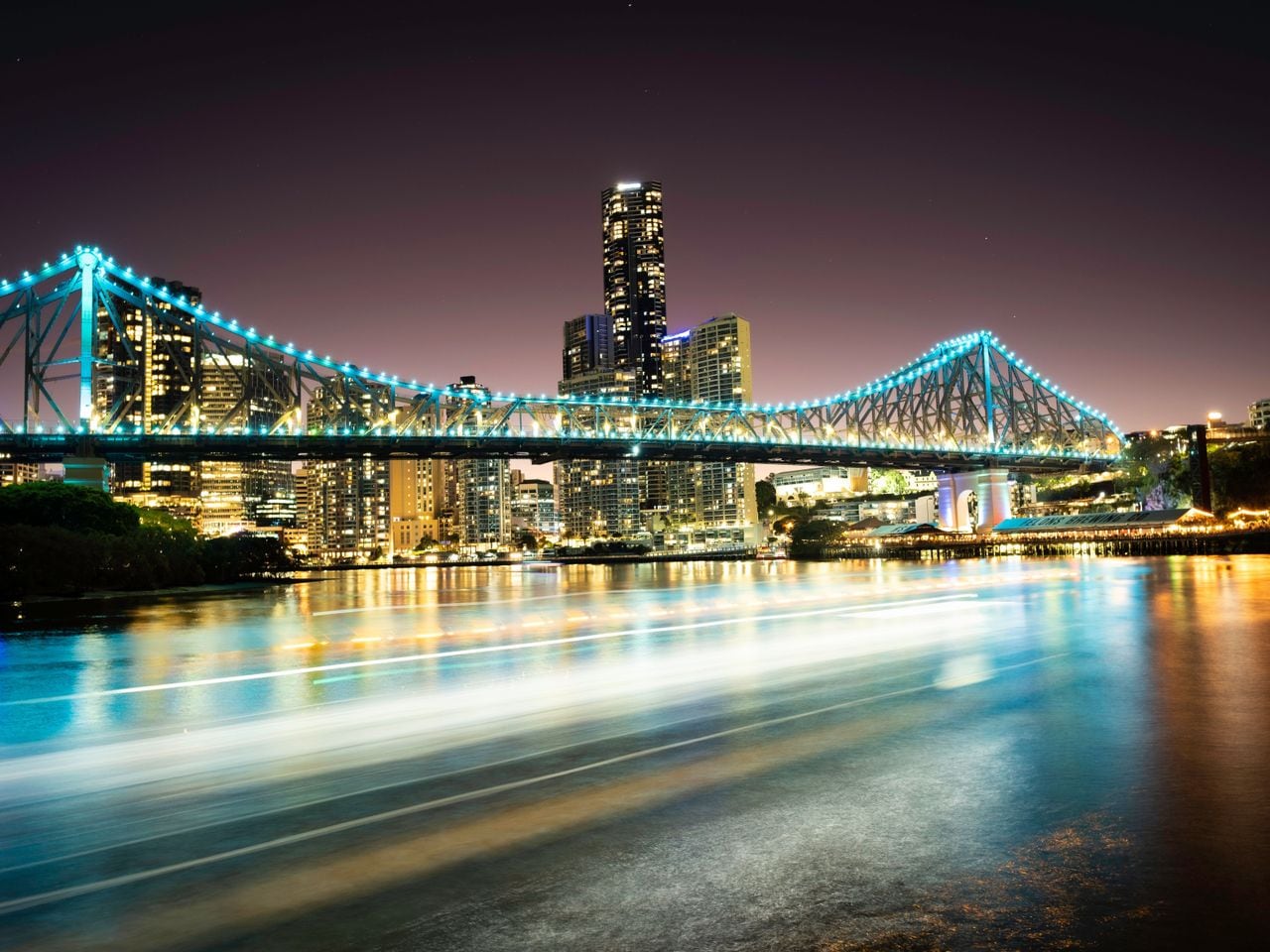Night view of Brisbane’s illuminated Story Bridge and city skyline over the Brisbane River.