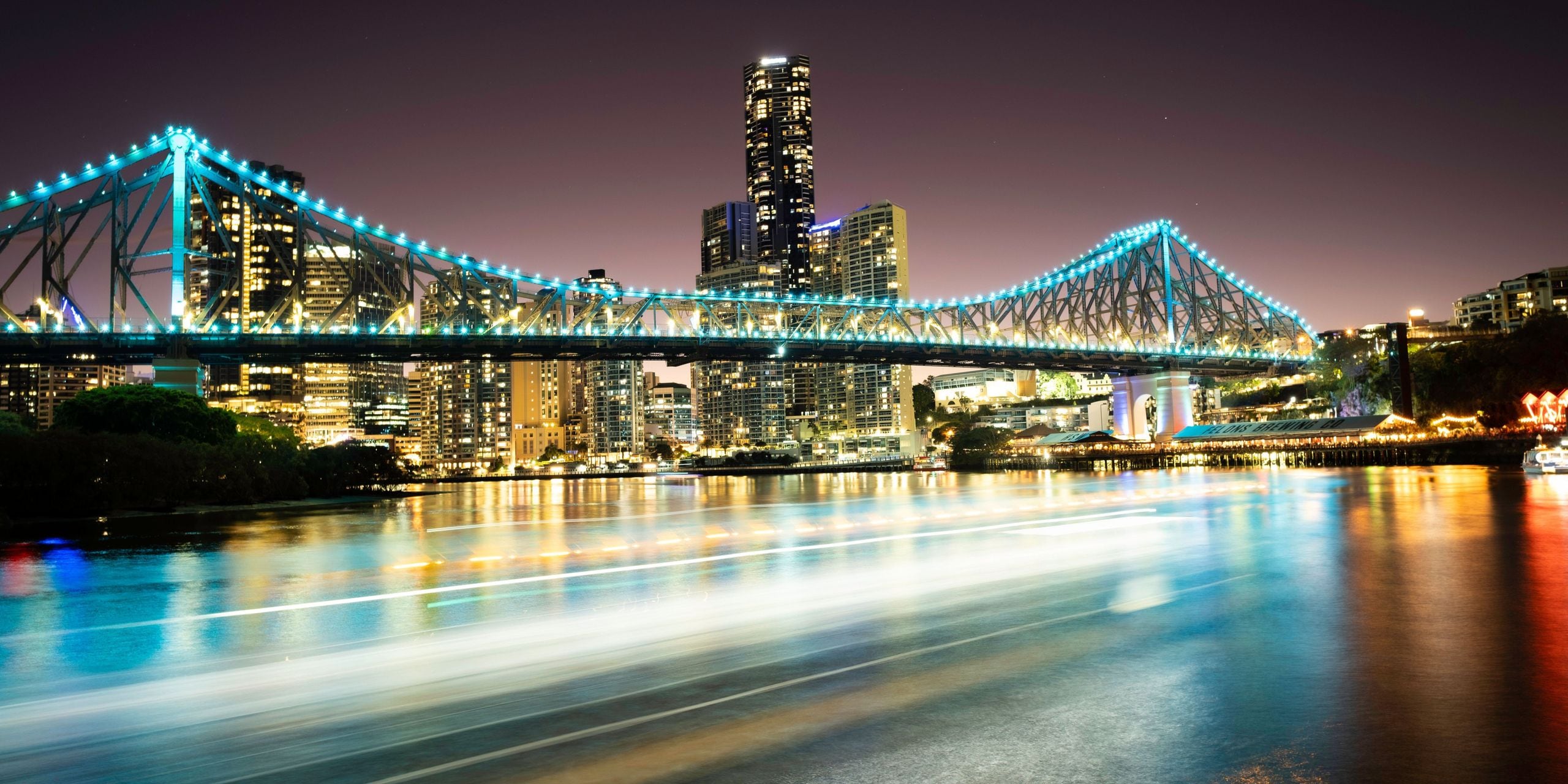 Night view of Brisbane’s illuminated Story Bridge and city skyline over the Brisbane River.